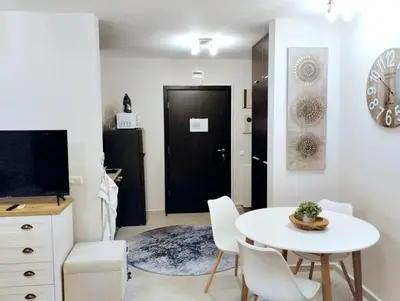 a living room with a white table and chairs and a black door at Spacious luxury studio with mountain view - SPA available in Bansko