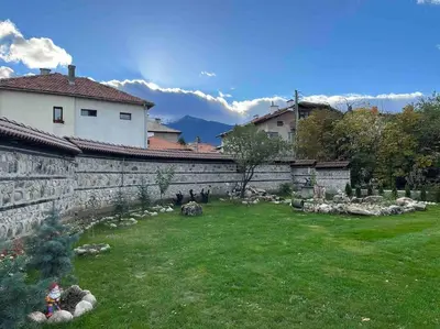 a garden with a stone wall and a yard with birds at Villa Fest in Bansko