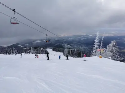 a group of people on a ski lift on a snow covered slope at Cozy Mountain Apartment in Borovets