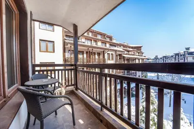 a balcony with two chairs and a table at Ski Lift Delight Bansko Apartment in Bansko