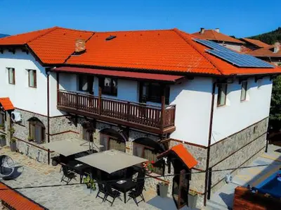 a building with an orange roof with tables and chairs at КЪЩА ЗА ГОСТИ ГРОШЪ in Dobrinishte