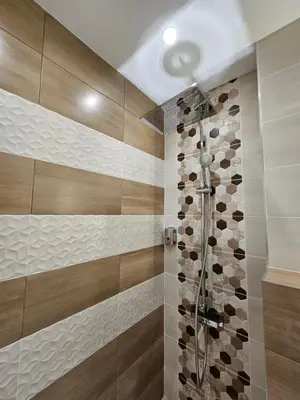 a bathroom with a shower with brown and white tiles at Villa Geronimo in Bansko