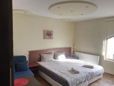 a bedroom with a bed and a blue chair at Dariya Guest House in Sapareva Banya
