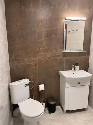 a bathroom with a white toilet and a sink at Двуспален апартамент в к-с Пирин Палас in Bansko