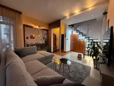 a living room with a large couch and a living room with a staircase at The Maisonette in Sofia's Heart in Sofia