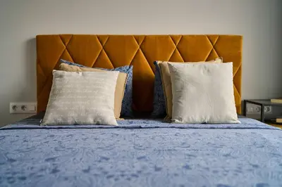 a bed with blue sheets and pillows with a wooden headboard at Scandinavian Stay - Awarded Bldg - Downtown in Sofia