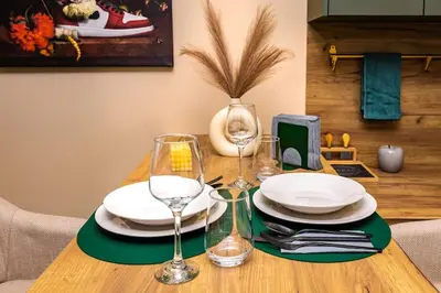 a wooden table with plates and wine glasses on it at Green Hills Plovdiv close to Medical University in Plovdiv
