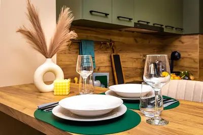 a wooden table with two plates and wine glasses at Green Hills Plovdiv close to Medical University in Plovdiv