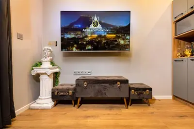 a room with two ottoman stools and a tv at Apollo Apartment close to Medical University in Plovdiv