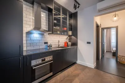 a kitchen with black cabinets and a wooden floor at SOHO 13 - Black & White in Sofia