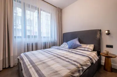 a bedroom with a bed with a plaid blanket and a window at SOHO 13 - Black & White in Sofia