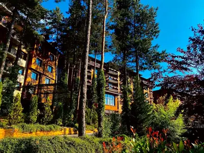 a building with trees and flowers in front of it at Апартамент Веирас in Velingrad