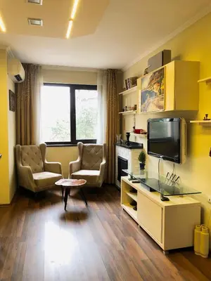 a living room with a tv and a couch and a table at Апартамент Веирас in Velingrad