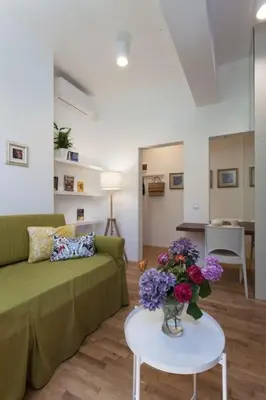 a living room with a green couch and flowers on a table at Gorgeous apartment in the perfect area in Sofia