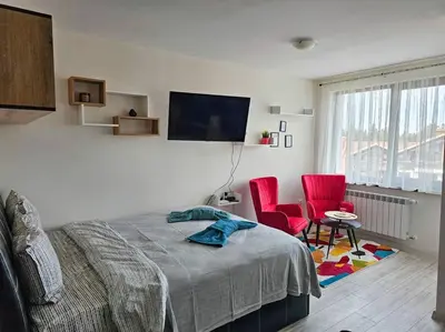 a bedroom with a bed and two red chairs at Boutique Studio B37 in Borovets