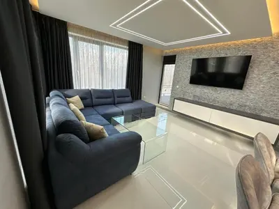 a living room with a blue couch and a tv at Regatta Park 2BR Exclusive Suite Parking Included in Plovdiv