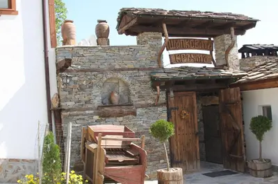 a stone building with an outdoor oven in a yard at Шапкова Къща in Delchevo