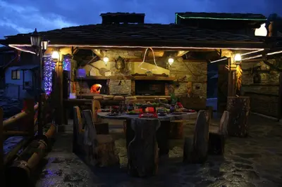 a table and chairs in front of a house at night at Шапкова Къща in Delchevo