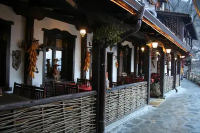 a restaurant with tables and chairs on a street at Шапкова Къща in Delchevo