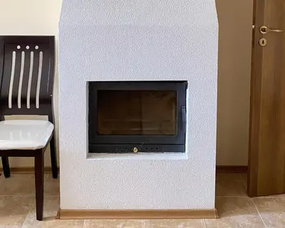 a white wall with a fireplace with a chair at 