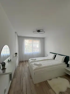 a white bedroom with a bed and a mirror at MidnightBlue Apartment in Bansko