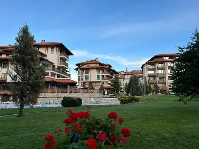 a group of apartment buildings in a park with flowers at MidnightBlue Apartment in Bansko