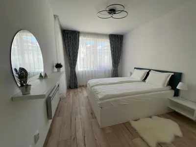 a white bedroom with a bed and a window at MidnightBlue Apartment in Bansko