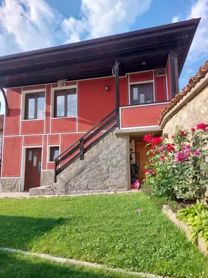 a red house with a stone wall at Стаи за гости Симона in Koprivshtitsa