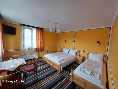 a hotel room with two beds and a table at Стаи за гости Симона in Koprivshtitsa