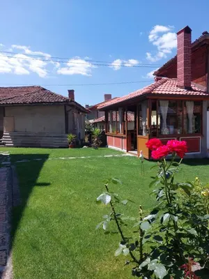 a house with a red rose in the yard at Стаи за гости Симона in Koprivshtitsa