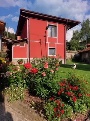 a red house with flowers in front of it at Стаи за гости Симона in Koprivshtitsa