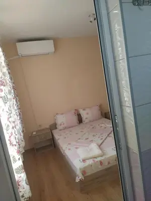 a small bedroom with a bed with pink pillows at Guest House Proynovi in Kalofer
