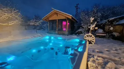a hot tub in the snow in front of a cabin at СПА къща за гости Каза Роза - Swiss Style Chalet Casa Rosa SPA Guest House in Kyustendil