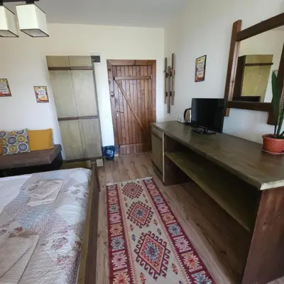 a room with a bed and a desk with a television at Guest House Belchin View in Belchin