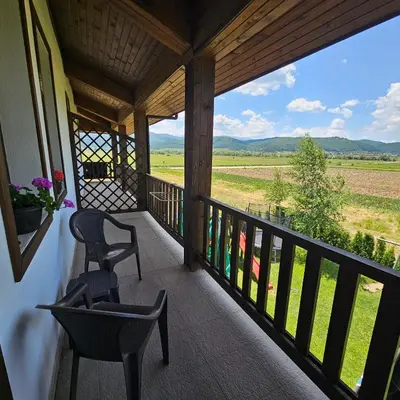 a porch with two chairs and a view of a field at Guest House Belchin View in Belchin