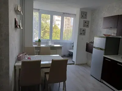 a kitchen with a table and chairs in a room at Тристаен апартамент in Sofia