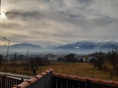 a person walking on a bridge with mountains in the background at Villa Detelina near the Bansko Ski Resort in Razlog