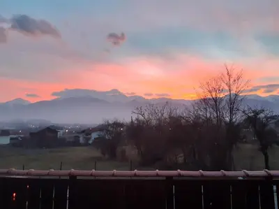 a sunset over a field with mountains in the background at Villa Detelina near the Bansko Ski Resort in Razlog