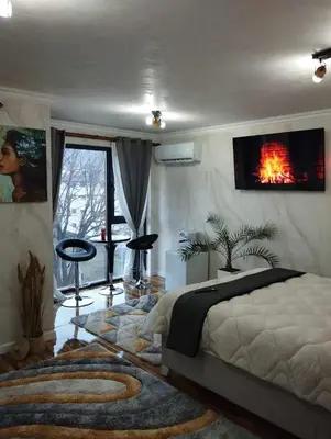 a bedroom with a bed and a tv on the wall at Апартамент за гости Боляри 2 in Velingrad