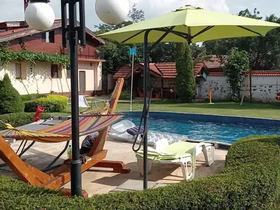 a hammock and an umbrella next to a pool at Vila Teo in Vasil Levski