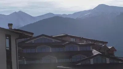 a large building with mountains in the background at Bansko Ski Apartments in Bansko Royal Towers in Bansko