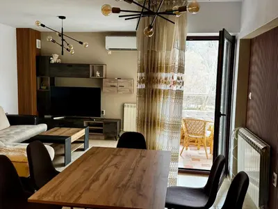a living room with a table and a couch and a television at Sunny Park Retreat in Sandanski