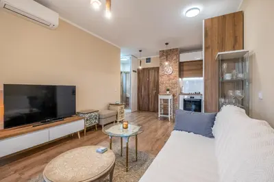 a living room with a white couch and a tv at The Lemons Cozy Apartment in Sofia