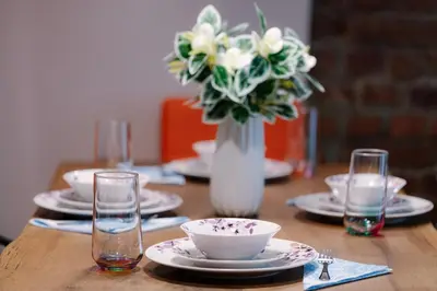 a wooden table with plates and a vase of flowers at 2 Designer Central Apartments FREE Parking Spaces in Sofia
