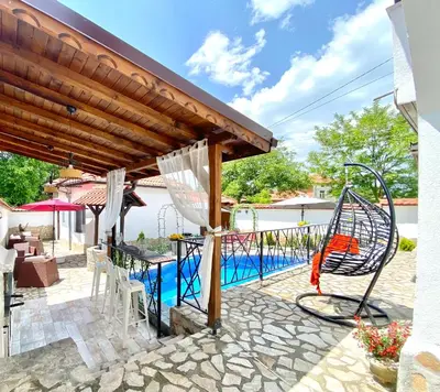 an outdoor patio with a swing and a pool at Къща за гости Casa Per Te село Огняново - село Марчево in Marchevo
