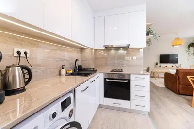 a kitchen with white cabinets and a stove top oven at Stylish One-Bedroom Apartment in Plovdiv
