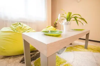a table in a room with a yellow ottoman at 19 Cozy Central Apartment with Balcony in Sofia