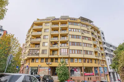 a tall yellow building with cars parked in front of it at 35 Cozy Central 1 Bedroom Apartment with Balcony in Sofia