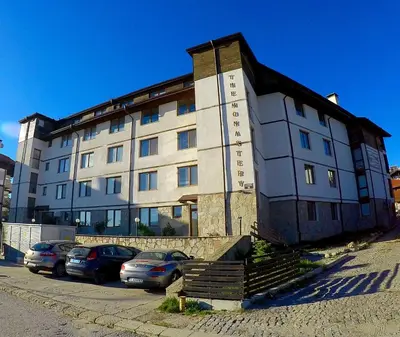 a large building with cars parked in front of it at Monastery Apartment C39 in Bansko