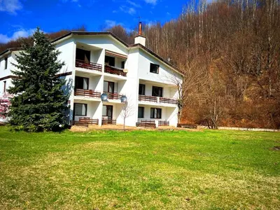 a large white building with a tree in a field at Вила и тенис комплекс ,,Синьото